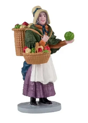 Gemüsehändlerin die traditionell gekleidet ist und Korb mit frischem Gemüse auf dem Rücken trägt.