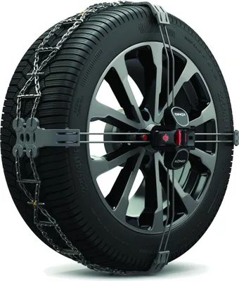 A close-up studio shot of a snow chain fitted onto a car tire and wheel.