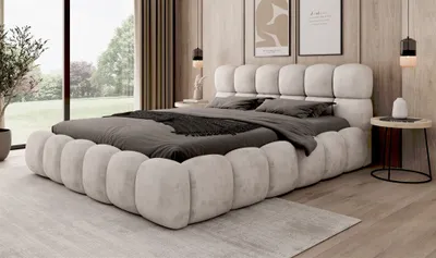 A modern bedroom with a large bed, bedside table, and artwork on the wall.