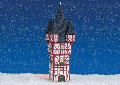 A miniature building, resembling a tower with a pointed roof, sits in a snowy landscape against a starry blue background.