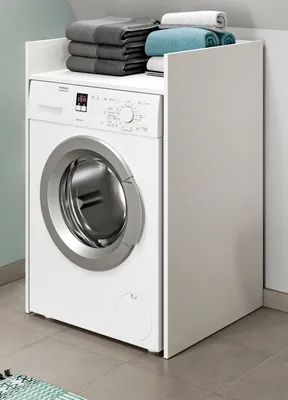 A white washing machine with a white cabinet on top, holding folded towels.