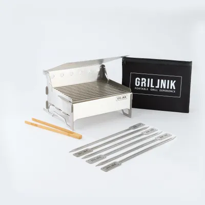 A portable stainless steel charcoal grill and its accessories are displayed on a white background.