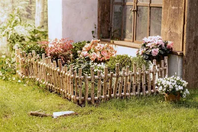A decorative wooden fence bordering a flower bed next to a building.