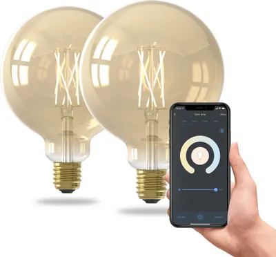 A hand holding a smartphone displaying a smart bulb app, with two smart LED bulbs in the background.