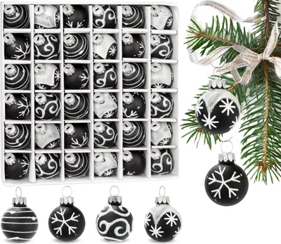 A box of black and white Christmas ornaments and some ornaments hanging from a tree branch.