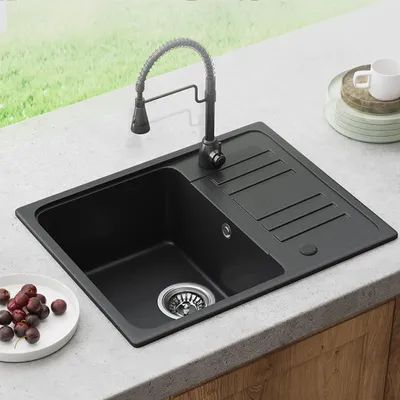 A black granite kitchen sink with a faucet and a small dish of cherries on a countertop.