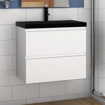 A white bathroom vanity with a black countertop and sink, mounted on a tiled wall.