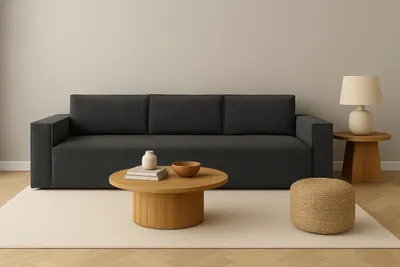 A modern living room scene with a dark gray sofa, a wooden coffee table, and a small woven pouf.