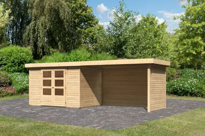 A wooden garden shed with an attached roof structure, set on a paved area surrounded by greenery and trees.