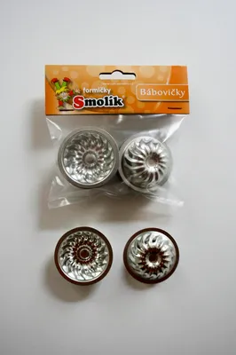 A package of four small, fluted baking molds for cakes, with two molds inside the packaging and two placed below it.