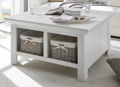 A white wooden coffee table with two woven storage baskets underneath, placed in a living room setting.