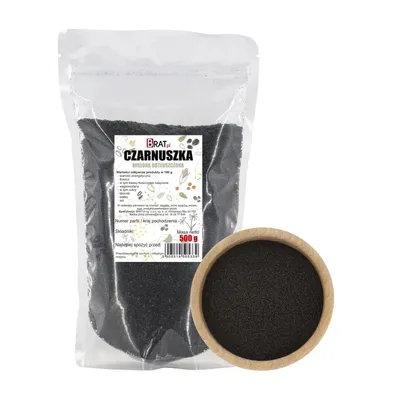 A bag of ground black cumin next to a wooden bowl filled with the same product.