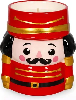 A ceramic nutcracker-shaped candle holder with a lit candle inside.