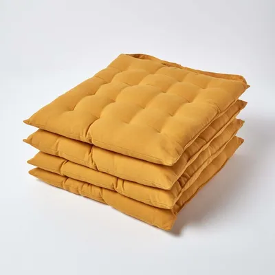 A stack of four mustard yellow seat cushions on a white background.