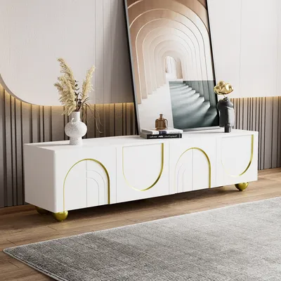 A white TV stand with gold accents is shown in a living room setting, with a large framed artwork behind it and a rug in front.