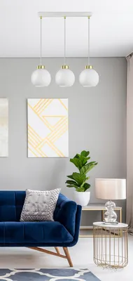 A modern living room with a blue sofa, a pendant light, and artwork on the wall.