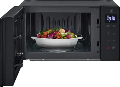 An open black microwave oven with a bowl of cooked vegetables inside.