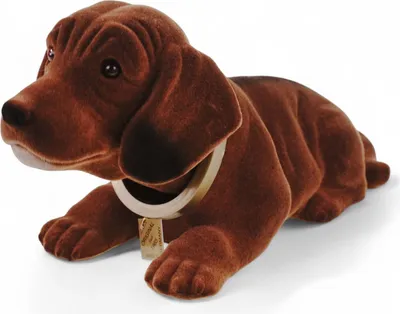 A brown plush dachshund figurine with a collar and tag, lying down on a white background.