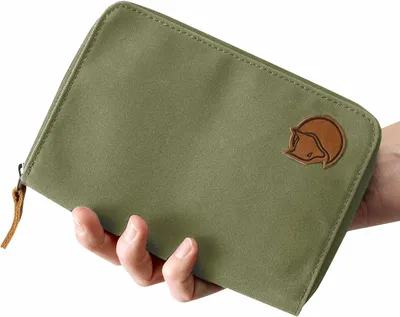 A hand holding a green passport wallet.