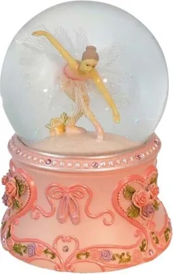 A snow globe with a ballerina figurine inside, displayed on a decorative pink base.