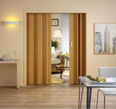 A room with a folding door, a sofa, a table, and a painting on the wall.
