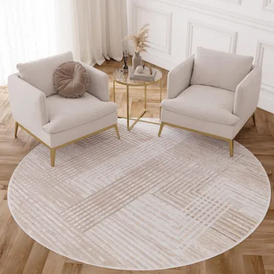 Two cream armchairs are placed on a round rug with a geometric pattern in a living room setting.