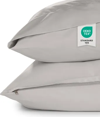 Two light gray pillowcases are stacked on top of each other, with a close-up view of the top pillowcase showing a certification tag.