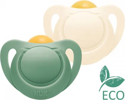 Two NUK pacifiers, one green and one cream colored, are shown against a white background. An 'ECO' leaf logo is visible in the lower right corner.