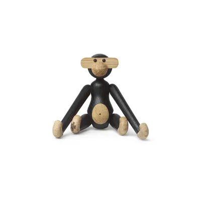 A small wooden monkey toy sitting on a white background.