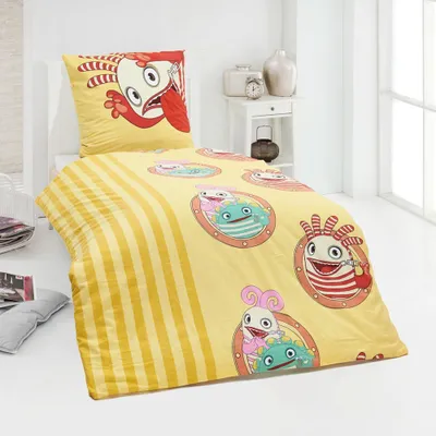 A bed with yellow bedding featuring cartoon monsters.
