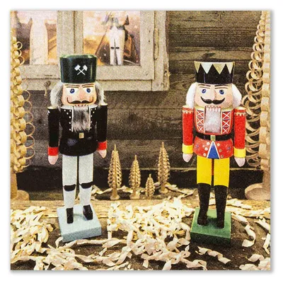 Zwei bunte Nussknackerfiguren stehen auf einem Tisch umgeben von Holzspänen und dekorativen Holzornamenten vor einem rustikalen Hintergrund mit einem Fenster.