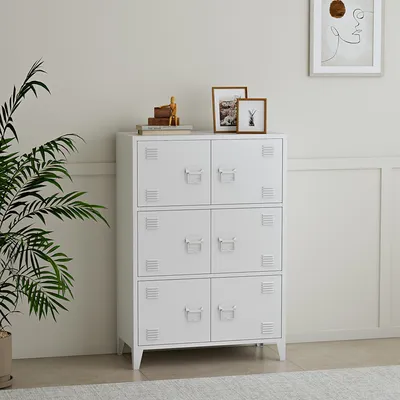 A white locker-style cabinet is shown in a room with a plant and framed pictures.