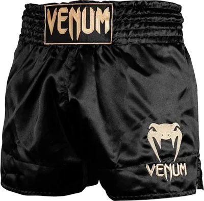 A pair of black Muay Thai shorts with gold branding.