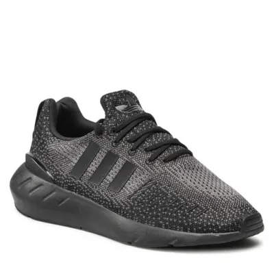 A studio shot of a single black Adidas sneaker.