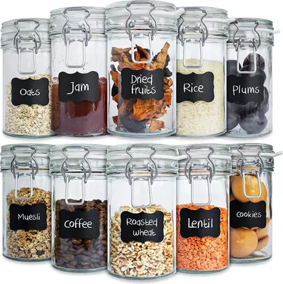 A collection of glass jars with clamp lids, each labeled with chalk-style stickers indicating their contents.