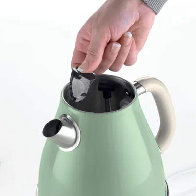 A hand is placing a filter into a green electric kettle.