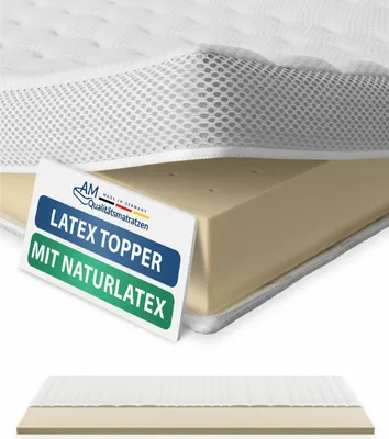 A close-up view of a latex mattress topper with a white quilted cover and a beige latex core, with a label indicating product details.