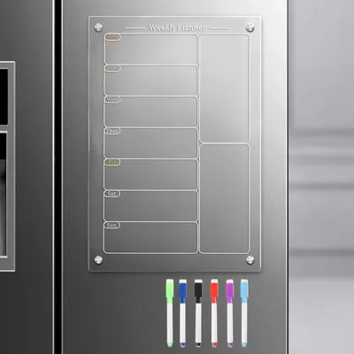 A magnetic acrylic weekly planner is attached to a refrigerator door, with a set of colorful dry-erase markers laid out below it.