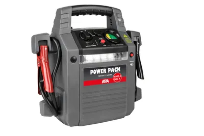 A gray portable power pack with red jumper cable clamps attached.