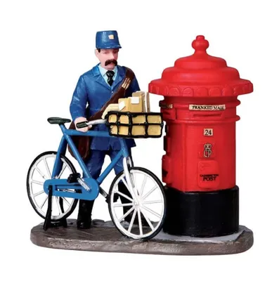 Ein britischer Postboten, der neben einem klassischen roten Briefkasten steht. 