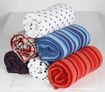 A stack of rolled-up fleece blankets with different patterns and colors.