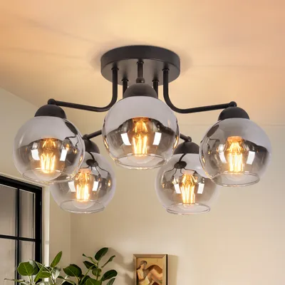 A black ceiling light fixture with five glass globes is shown against a light-colored ceiling and wall.
