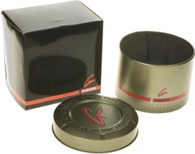 A black box, a cylindrical metal tin, and a circular lid, all branded with the G-Shock logo, are arranged on a white background.