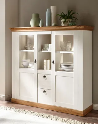 A white and wood-colored highboard cabinet with glass doors and drawers, filled with decorative items and dishes.
