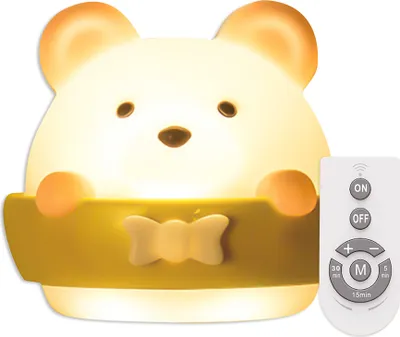 A cute, glowing bear-shaped night light is shown with a remote control next to it.