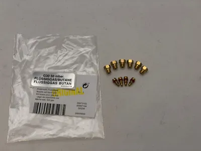 A set of gas nozzles in a plastic bag next to several loose nozzles on a light gray surface.