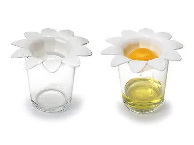 Two glasses, each with a white flower-shaped egg separator on top. The left glass is empty, while the right glass shows an egg yolk separated from the egg white.
