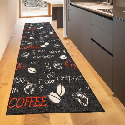 A black rug with coffee-themed text and graphics is laid out on a wooden floor in a hallway next to kitchen cabinets.