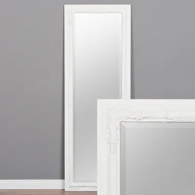 A full-length mirror with a white baroque frame stands against a gray wall. A portion of a second, similar mirror is visible in the foreground.