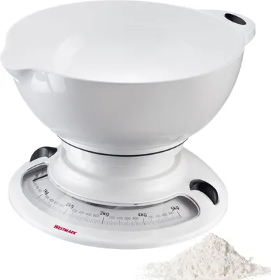 A white kitchen scale with a mixing bowl on top, next to a pile of flour.
